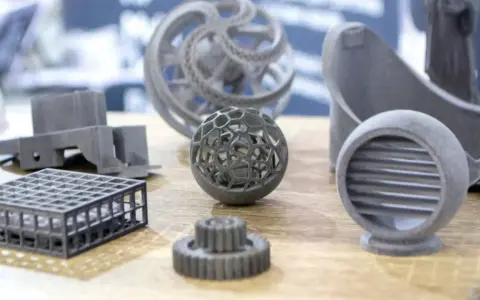 A collection of intricate 3D printing spare parts, including a lattice sphere, gears, and a vent, showcasing advanced manufacturing capabilities.