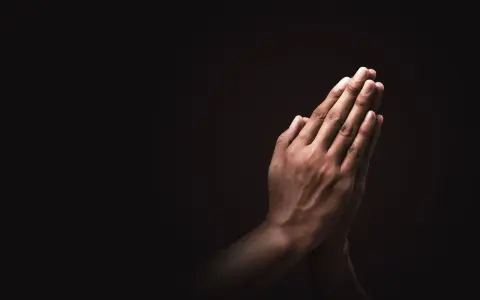 Dłonie złożone do modlitwy, symbol nadziei i siły w walce o trzeźwość.