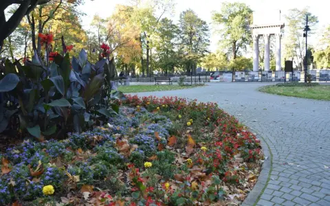 Jesienny park strzelecki Tarnów. Kolorowe rabaty kwiatowe i liście na brukowanej ścieżce.