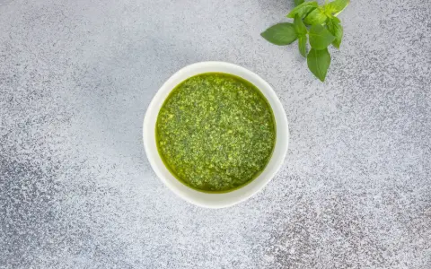 Frisches Basilikum und ein Schälchen mit selbstgemachtem Pesto. Ein einfaches Pesto Rezept für Pasta.