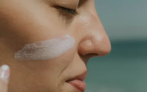 Rostro de mujer con una pincelada de crema solar biodegradable en la mejilla.