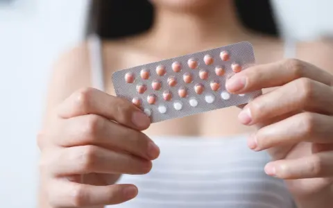 Frau hält Blisterpackung mit Pillen. Bei der Entscheidung, die Pille durchzunehmen, sind Nebenwirkungen zu beachten.