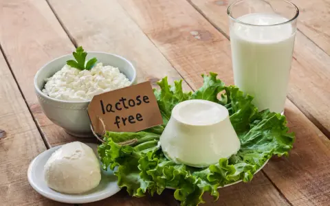 Serek wiejski, kulka mozzarelli i ser w kształcie stożka na sałacie, obok szklanki mleka. Etykieta głosi "lactose free", co oznacza brak laktozy.