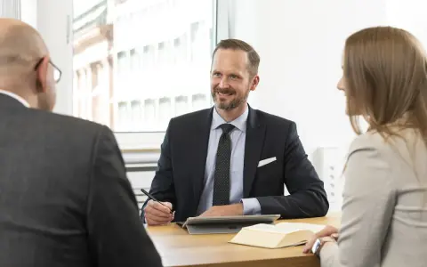 Anwalt für Versicherungsrecht bietet kostenlose Erstberatung. Drei Personen im Gespräch am Tisch.