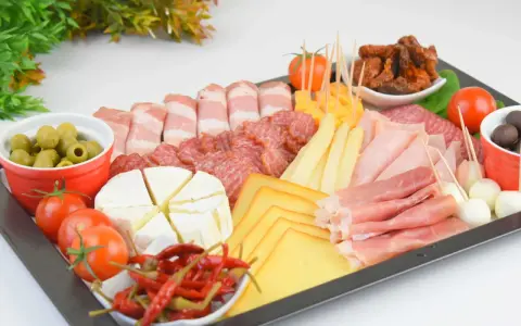 Deska wędlin jak przygotować: różnorodne sery, wędliny, oliwki, pomidorki i papryczki chili. Idealna na spotkanie.