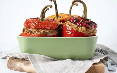 Saftige peperoni ripieni, gefüllt mit Hackfleisch und Reis, in einer grünen Auflaufform.