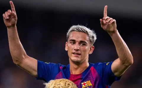 Pablo Gavi, con el pelo teñido de rubio, levanta los brazos y señala al cielo, celebrando un gol.