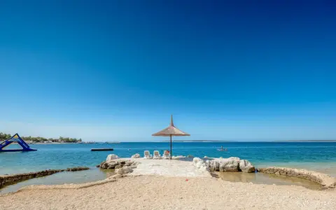Słoneczny dzień na plaży w Simuni camping. Leżaki pod parasolem, dmuchany plac zabaw w wodzie i błękitne morze.