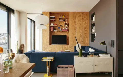 Un salón moderno con sofá azul, estanterías de madera y lámparas colgantes. Un espacio acogedor para **tini living**.