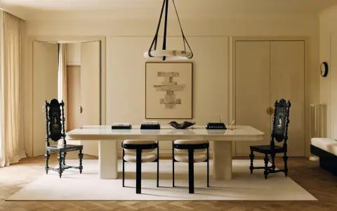 Comedor elegante con mesa blanca, sillas negras y una paleta de colores crema. Arte abstracto y cortinas suaves complementan el espacio.