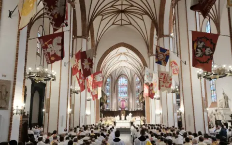 Wielki Czwartek post. Uroczysta msza w katedrze z udziałem duchowieństwa i wiernych, ozdobionej historycznymi sztandarami.