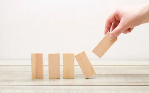 Main d'une personne retire un bloc de bois, faisant tomber les autres. Une métaphore des percers narcissiques qui déstabilisent leur entourage.