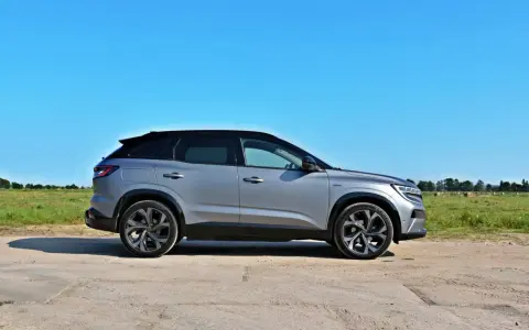 Nowy Renault Austral w kolorze srebrnym, zaparkowany na polnej drodze, z zielonym polem i niebieskim niebem w tle.