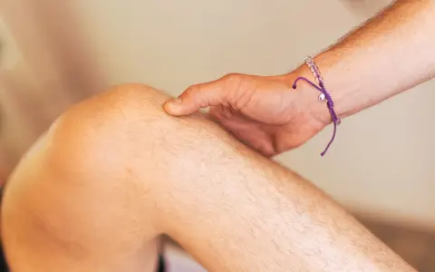 Ein Finger tastet das Knie ab, als ob ein Schleimbeutel im Knie geplatzt wäre.