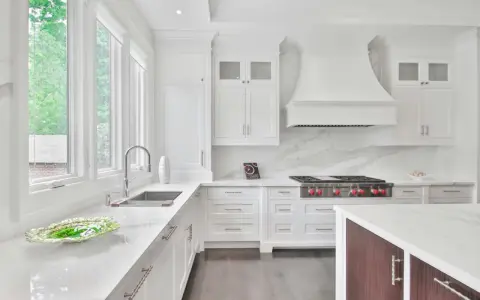 Cocina moderna y luminosa con muebles blancos, encimeras de cuarzo y electrodomésticos de acero inoxidable. Perfecta para pintar muebles de cocina y darles un nuevo aire.