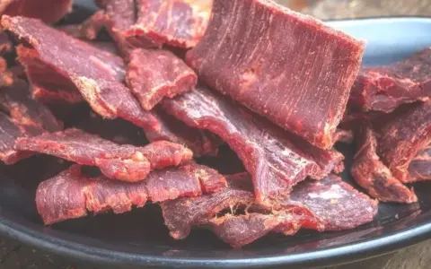Suszone plastry wołowiny na czarnym talerzu. Idealne do przekąski, gdy szukasz prostego beef jerky przepis.