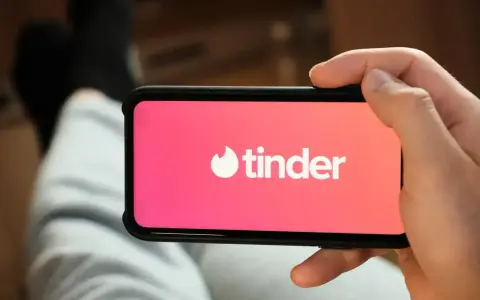 Dłoń trzyma smartfon z logo popularnych portali randkowych Tinder.