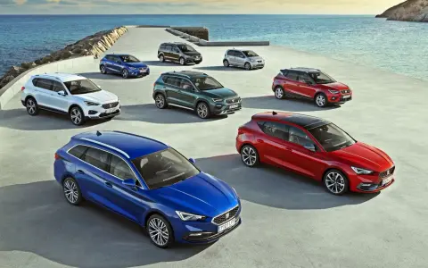 Różnorodne modele SEAT stojące nad morzem. Wśród nich biały SUV, niebieski kombi i czerwony hatchback.