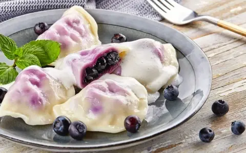 Pyszne pierogi z jagodami, polane śmietaną, z miętą i świeżymi owocami. Idealny przepis na lato!