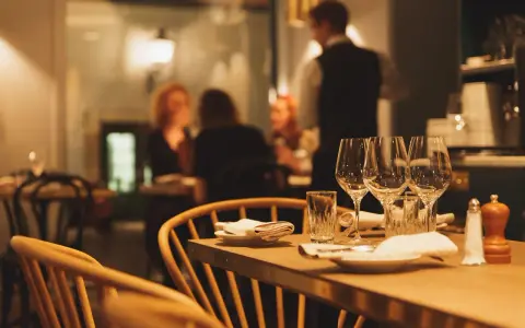 Ett dukat bord med vinglas och servetter, redo för en matvandring i Stockholm. I bakgrunden syns gäster och personal i en mysig restaurangmiljö.