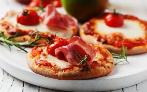 Pizzerinki z serka wiejskiego, pomidorkami koktajlowymi i szynką parmeńską, ozdobione rozmarynem.