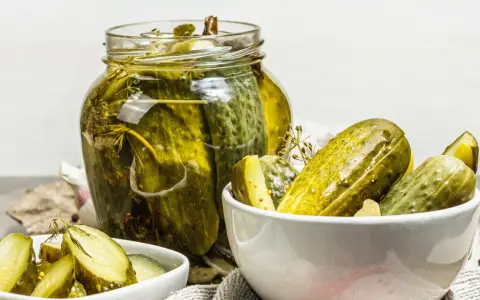 Vaso di cetriolini in agrodolce, con alcuni in una ciotola. Perfetti per un antipasto croccante e saporito.