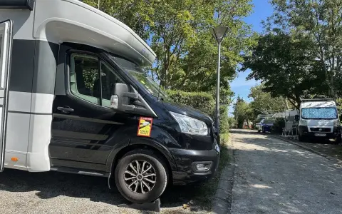 Husbil parkerad på en campingplats vid frankrike kust. Soligt väder med träd och andra husbilar i bakgrunden.
