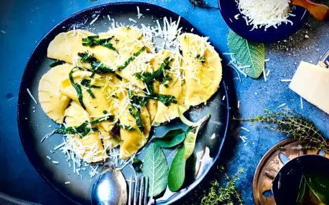 Frische Ravioli, ein italienisches Gericht, mit geriebenem Parmesan und Kräutern garniert. Das Ravioli-Teig Rezept italienisch ist hier perfekt umgesetzt.