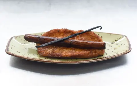 Torrijas de leche y canela, doradas y crujientes, con una rama de canela y vainilla. ¡Perfectas para aprender como hacer torrijas de leche y canela!