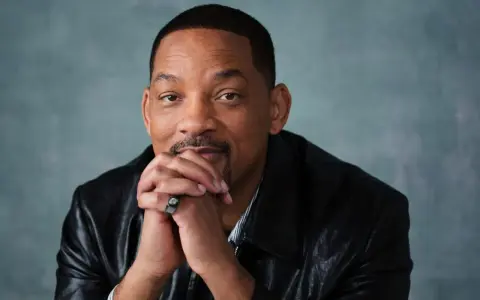 Will Smith, känd från många filmer och tv-program, sitter med händerna knäppta framför sig.