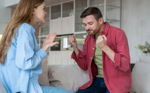 Coppia in conflitto, lei gesticola con rabbia, lui stringe i pugni. Una scena che illustra le difficoltà nel come convivere con un narcisista.
