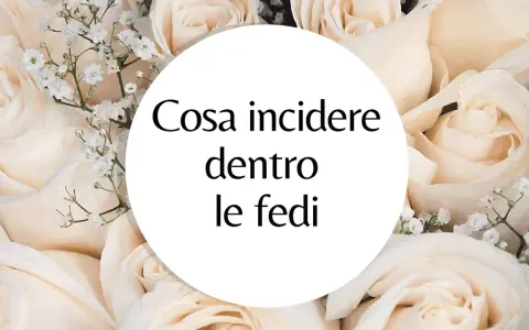 Un cerchio bianco su uno sfondo di rose color crema con la domanda: "Cosa incidere dentro le fedi?". Ispirazione per incisioni fedi nuziali frasi.