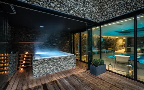 Relaks w nowoczesnym spa na Dolnym Śląsku: jacuzzi z kamienną obudową, basen i nastrojowe oświetlenie.