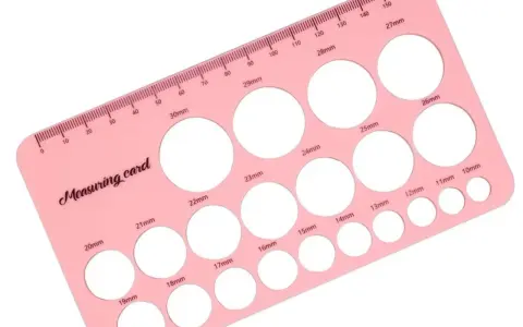 Różowa karta pomiarowa z otworami o różnych średnicach, od 10mm do 30mm, pomocna przy tworzeniu kapturków do karmienia.