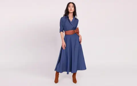 Modelka w niebieskiej sukience z brązowym pasem i botkami. Brązowy to kolor, jaki pasuje do niebieskiego, tworząc elegancką stylizację.