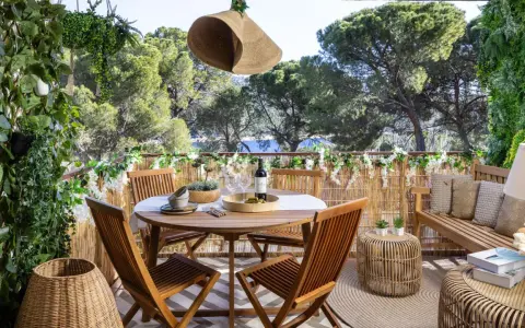 Encantadora decoracion terrazas con mesa de madera, sillas, banco y mucha vegetación. Un oasis verde para disfrutar del aire libre.