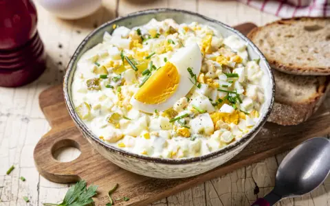 Cremiger Eiersalat mit Gurken und Kräutern, garniert mit einem Ei-Viertel. Ein köstliches eiersalat rezept für jede Gelegenheit.