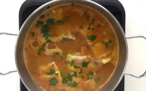 Guiso de corvina burbujeante con perejil picado, listo para servir. ¡Perfecto para tus recetas de corvina guisada!