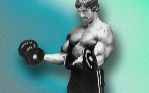Arnold Schwarzenegger beim Bizeps-Training. Er macht konzentrierte Wiederholungen für sein Hypertrophietraining.