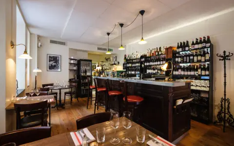 Mysig vinbar med trägolv, bardisk och hyllor fyllda med flaskor. Perfekt för att läsa bouchon recensioner över ett glas vin.