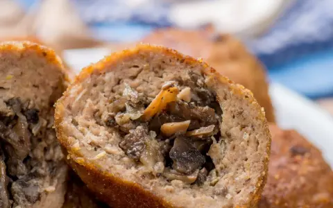Kotlety mielone z pieczarkami, jeden przekrojony, ukazujący soczyste nadzienie.