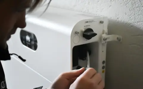 Person kopplar in en kabel i ett vitt system för att lagra solenergi batteri.