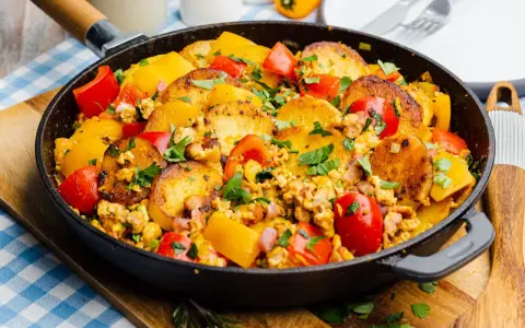 Herzhafte bauernpfanne mit kartoffeln und ei, garniert mit frischer Petersilie und bunten Paprikastücken. Ein deftiges Gericht direkt aus der Pfanne.