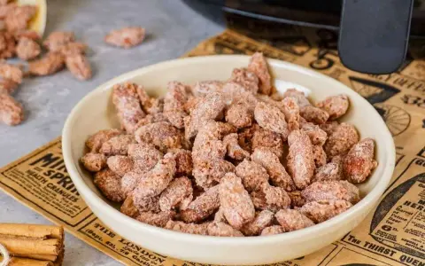 Schüssel mit gerösteten Mandeln, die mit Zimt und Zucker bestreut sind. Ein gesunder Snack, der gut schmeckt.