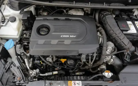 Silnik CRDi 1.6V w samochodzie. Widoczny czarny plastikowy dekiel silnika z napisem CRDi 16V, elementy układu dolotowego i chłodzenia.