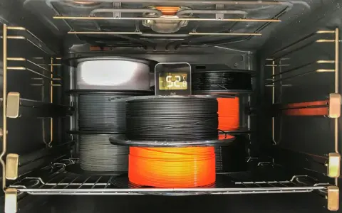 Szpule filamentu do druku 3D, materiał higroskopijny, suszone w piekarniku. Termometr pokazuje 52.8°C.