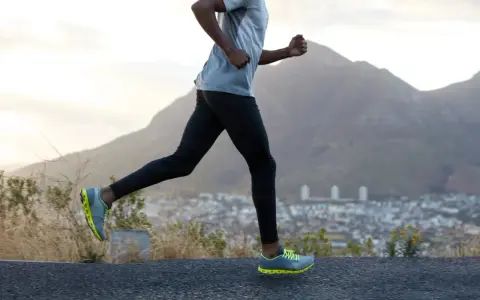Un homme court sur une route, profitant d'un exercice cardio avec une vue sur la ville et les montagnes.