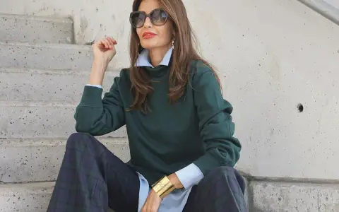 Elegancka kobieta po 50-tce w zielonej bluzie i kratkowych spodniach. Stylowe moda po 50-tce stylizacje.
