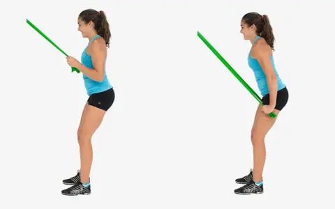 Kvinnlig atlet utför triceps pushdown med ett grönt träningsband.