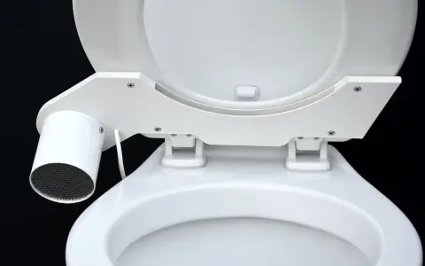 En vit toalett med en innovativ SOG-lösning. En liten cylinder med galler sitter monterad på sidan av sitsen.